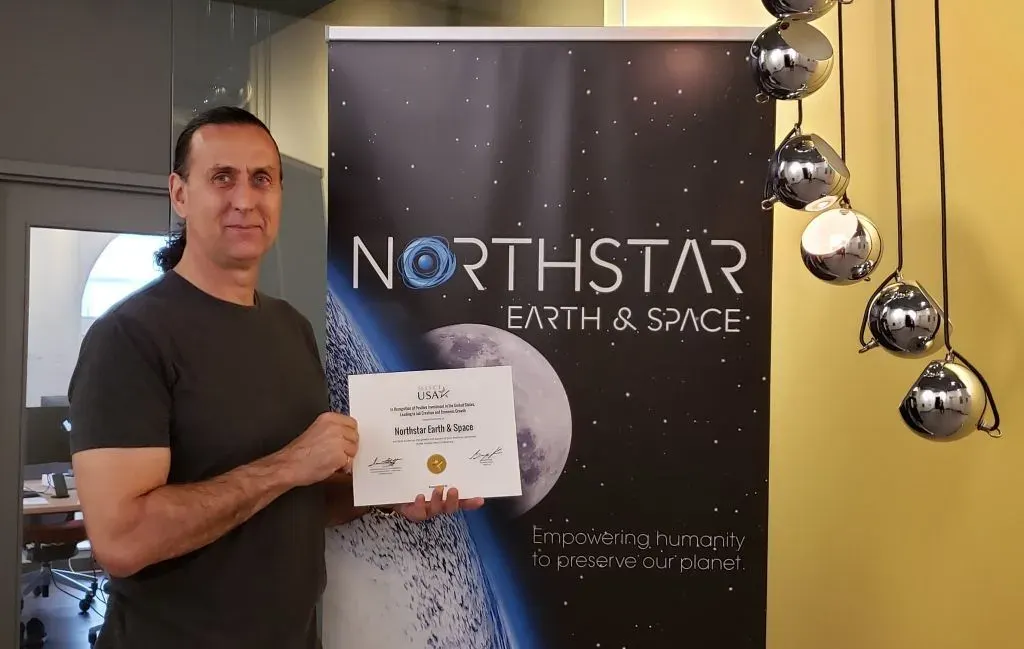 NorthStar Earth & Space founder and CEO holding a U.S. Department of Commerce award at company headquarters.