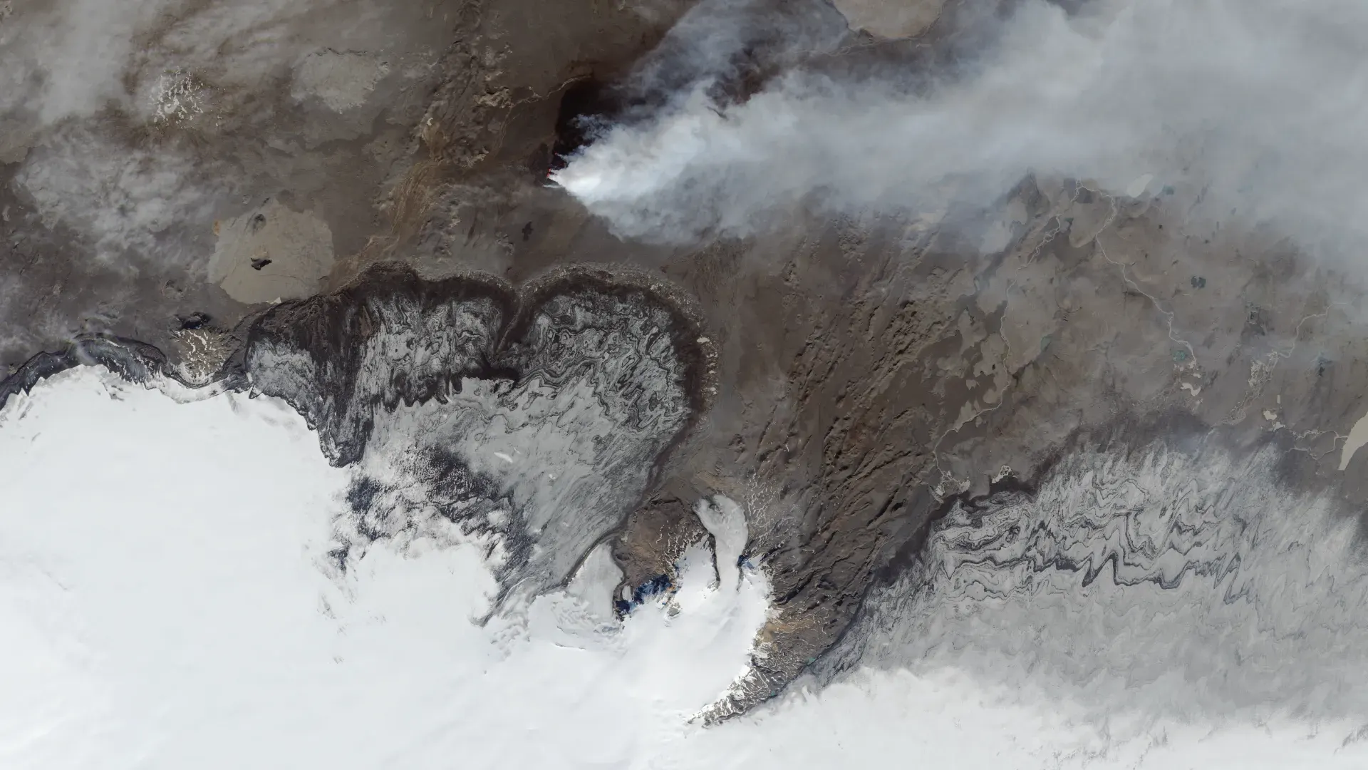 High resolution satellite image of rugged terrain with coastal shoreline, ice, and cloud cover